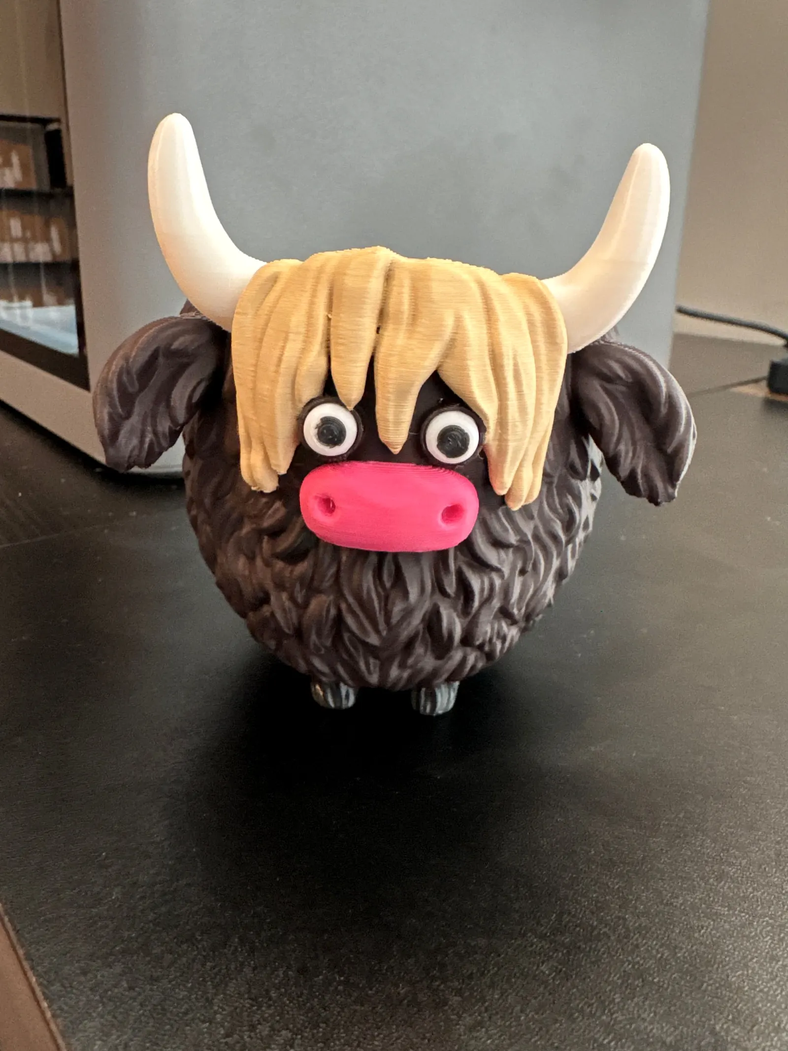 Round dark-brown Highland cow planter with a blonde fringe, cream horns and a pink nose