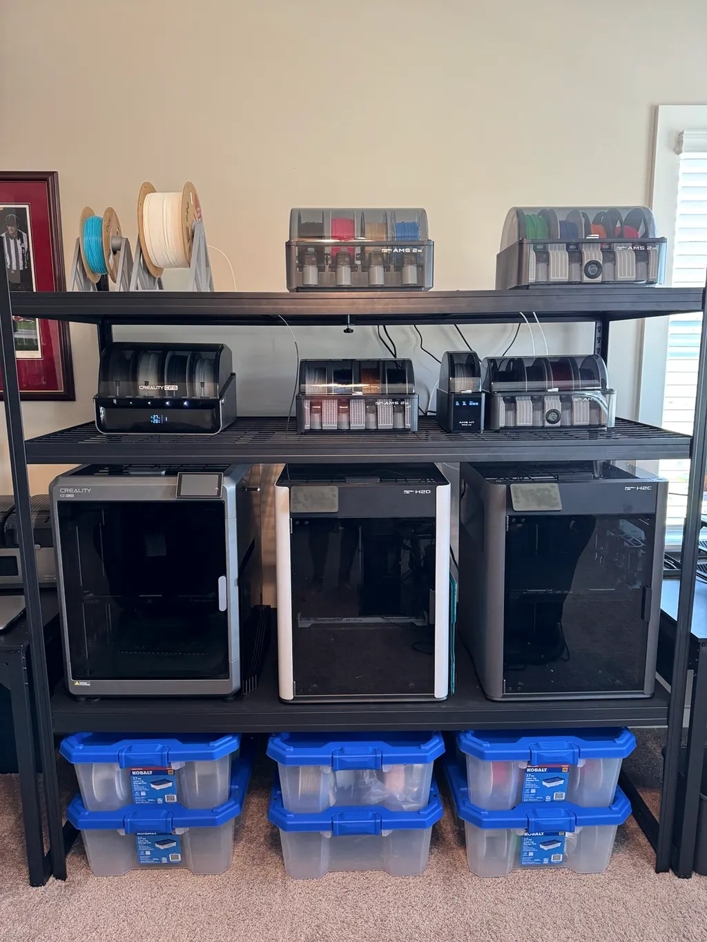 Three printers on one rack, each with its multi-material filament system on the shelf above.