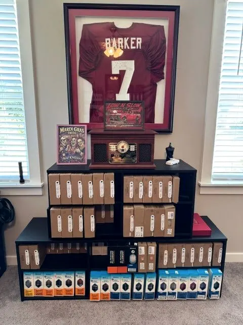 Shelves of boxed filament beneath a framed jersey, with finished HueForge pieces on display.